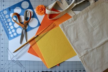 Orange, yellow and red felt alongside scissors, a ruler, a pencil, a plain tote bag and a few stencils