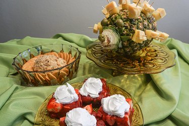 A pineapple and cheese hedgehog, a cheese ball with crackers, and Jello salad squares topped with Cool Whip