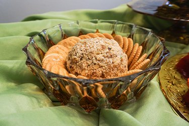A cheese ball sits in a dish surrounded by crackers