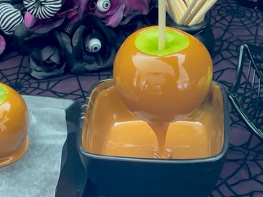 Letting excess caramel drip off the apple