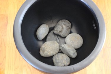 Rocks in bottom of black plastic cauldron.