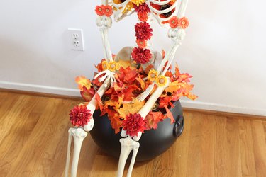 Skeleton sitting on cauldron.