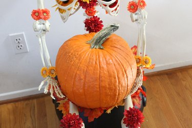 Pumpkin in skeleton's lap.