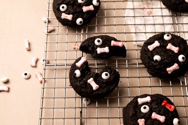 Chocolate cookies with bone and eye sprinkles on a wire rack