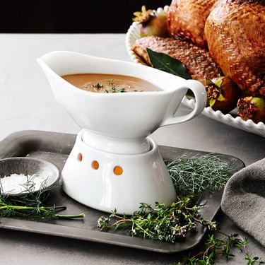 Porcelain white gravy boat with a warming base that contains a tea light inside of it.