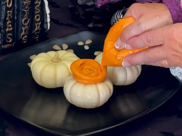 piping cream cheese onto mini pumpkins to create Sanderson Sisters' hairdos