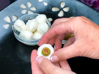 inserting green pimento olive into mozzarella cheese ball