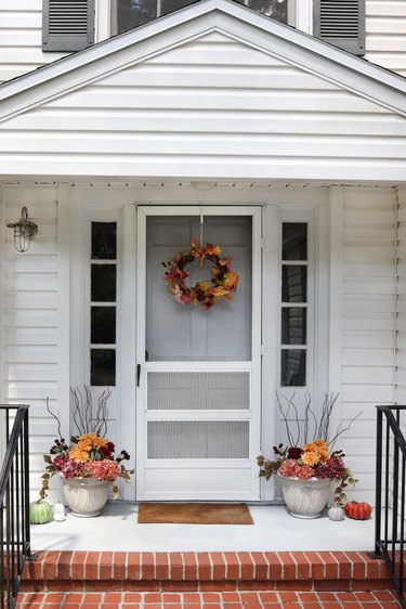 Fall wreath and planters on porch with pumpkins