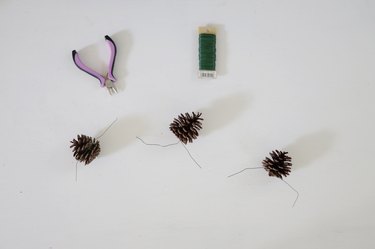 Three pine cones with floral wire attached to them