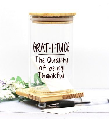 Clear glass gratitude jar, reads "The Quality of being Thankful"