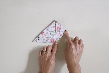 Folding floral paper into a bookmark and creasing the fold