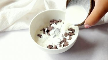 Pouring heavy cream into bowl with chocolate chips.