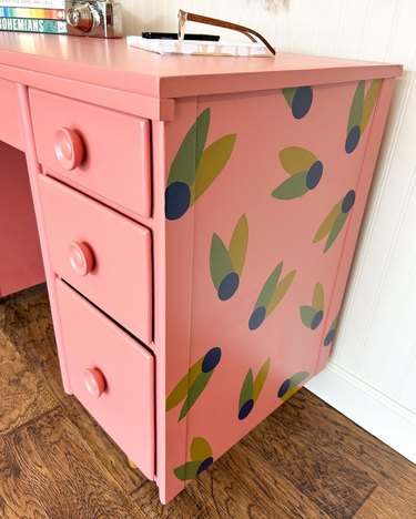 Pink desk with green and blue leaves painted on side