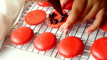 Piping chocolate ganache on bottom macaron shell.