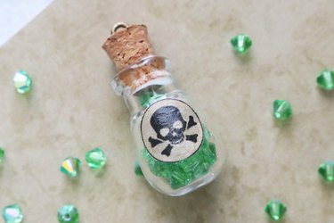 Glass bottle pendant filled with green crystal beads