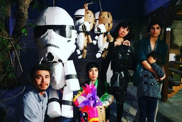 A group of people stand next to Star Wars–themed piñatas