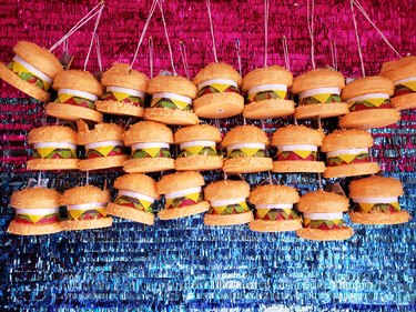 Mini burger piñatas hanging against a glittery pink and blue backdrop