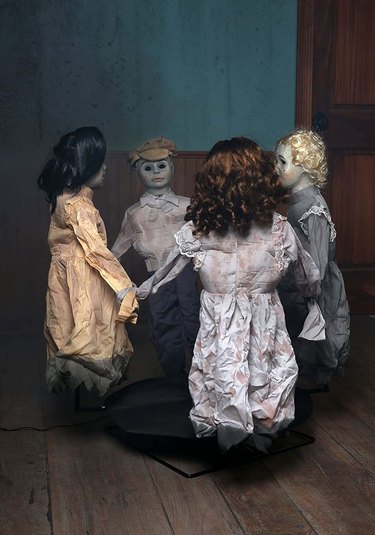 Four creepy dolls holding hands in a circle. They sing "Ring Around the Rosie."