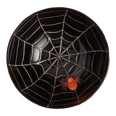 Black and white striped ceramic candy bowl with a spider web and an orange spider on the interior.