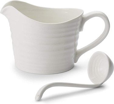 A mug-shaped white porcelain gravy dish with a pour spout and small white porcelain ladle