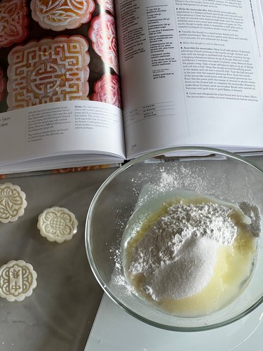 ingredients in a bowl and book spread and mooncake molds