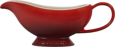 A classically shaped elongated, deep red stoneware gravy boat