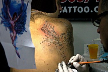 A tattoo artist stencils an image before beginning the line work.