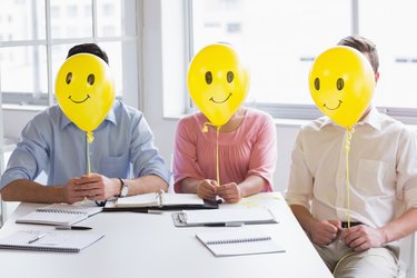 Business people holding balloons in front of face