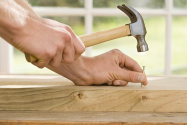 Hands hammering nail into wood