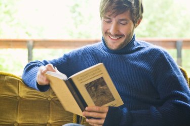 Man reading book and sitting on sofa