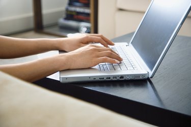 Hands typing on laptop