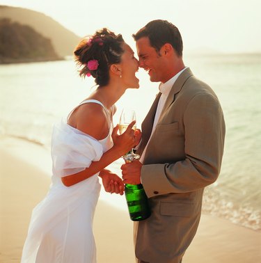 Bridal couple sharing champagne on beach