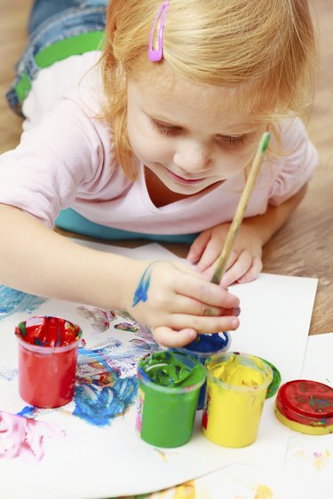 Cute little redhead girl painting.