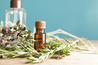 Bottle with aromatic oil and rosemary on a wooden table.