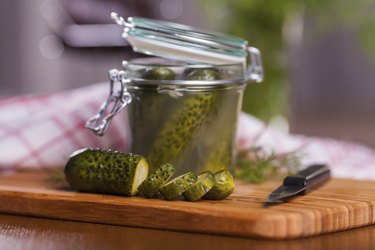 Pickled cucumbers in jar on cutting board