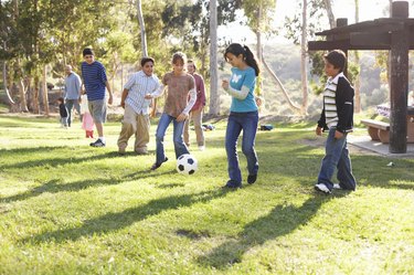 Children (9-14) playing soccer in park