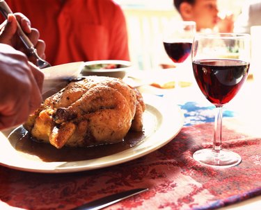 Hands carving roast chicken