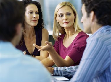 Side view of three mid adult people sitting and talking