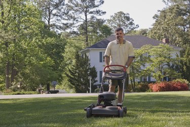 Smiling man mowing lawn