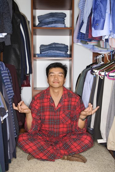 Man in pajamas sitting in yoga position in closet