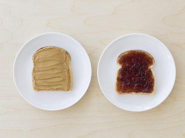 Slices of bread on plates with peanut butter and jelly