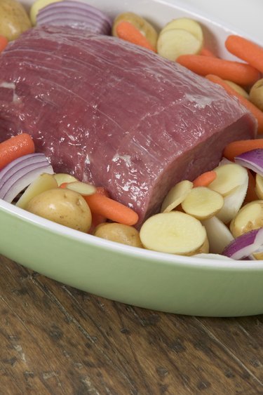 Uncooked pot roast on a bed of vegetables