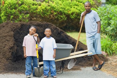 Mid adult man and his two sons holding shovels