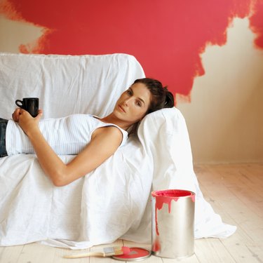 Side profile of a young woman lying on a covered couch with a coffee mug