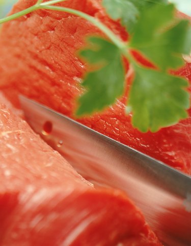 Raw beef with meat cleaver and herb, close-up
