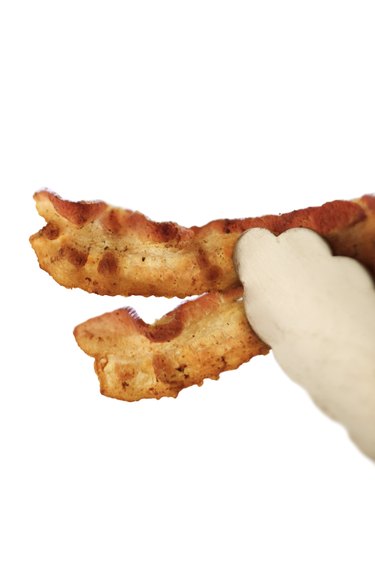 Tongs holding bacon