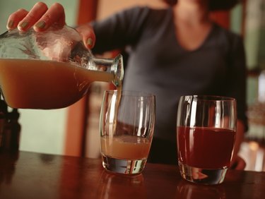 Woman pouring drink into glasses at bar, close-up
