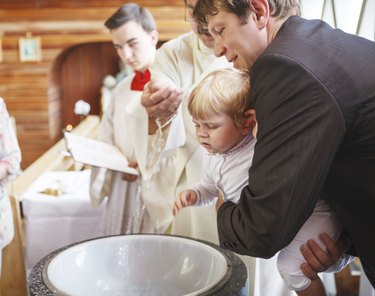 Little baby boy being baptized in catholic church holding