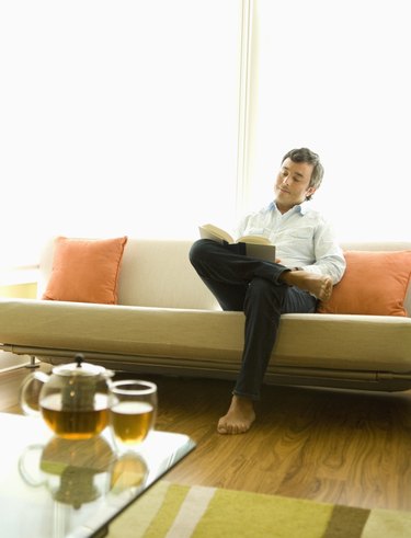 Hispanic man reading on sofa