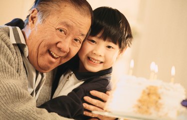 Senior man hugging grandson with birthday cake